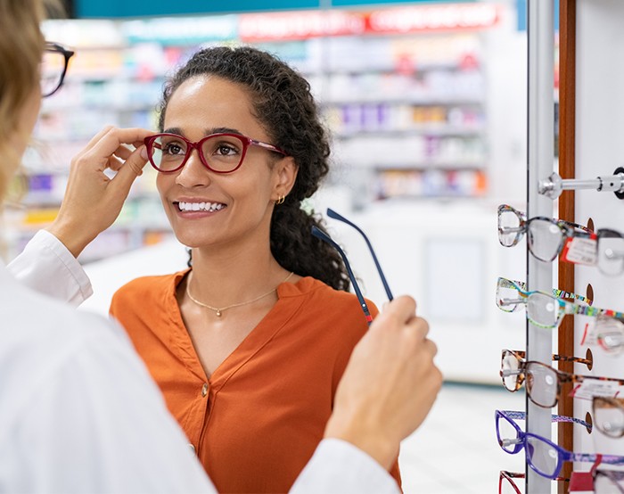 Eye doctor helping woman try on a variety of glasses to find the right pair