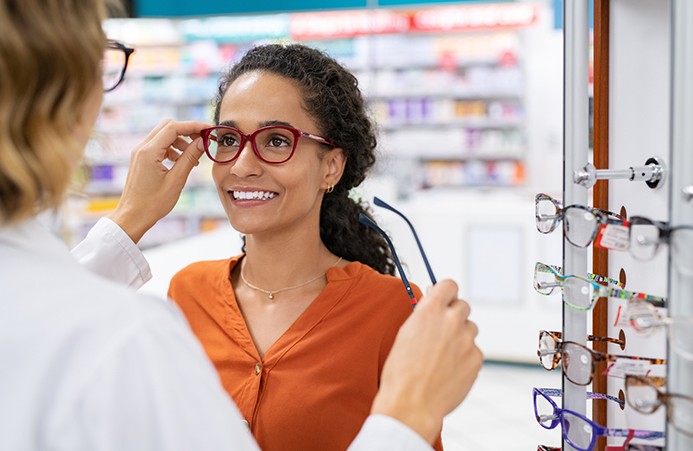 Eye doctor helping woman try on a variety of glasses to find the right pair
